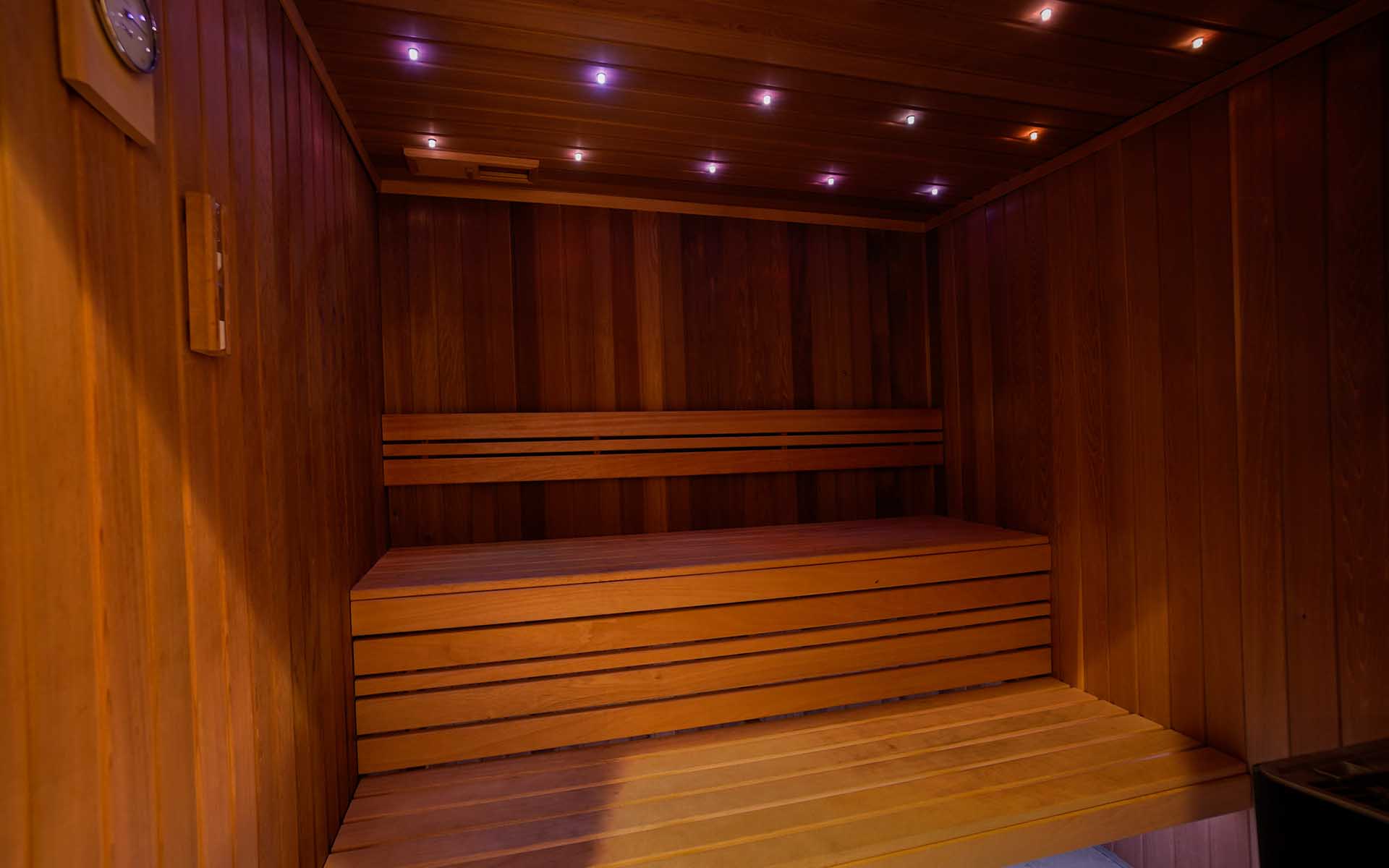 Sauna fińska z drewnianymi ławami i kolorowym oświetleniem