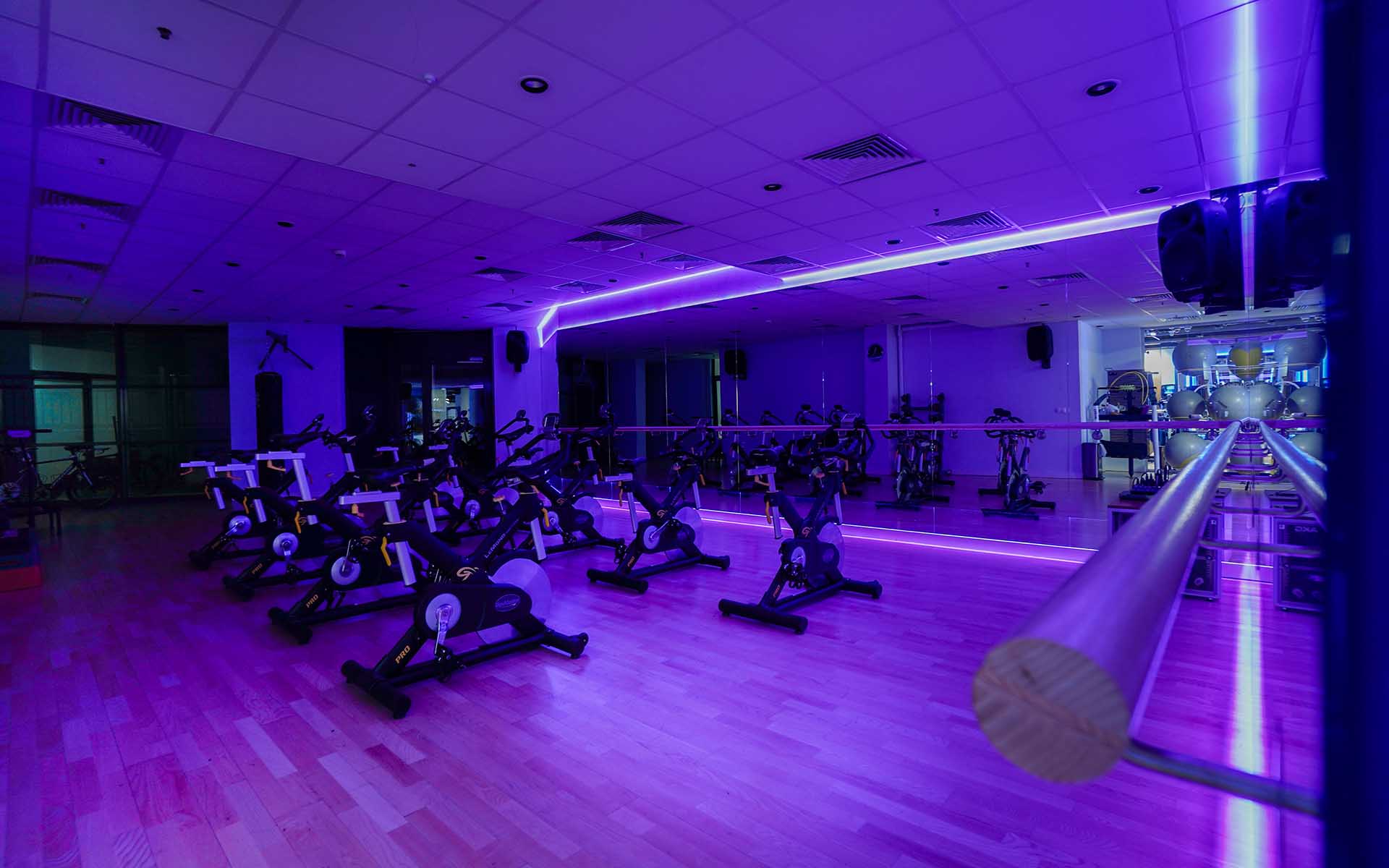 Studio fitness z rowerami spinningowymi w fioletowym oświetleniu